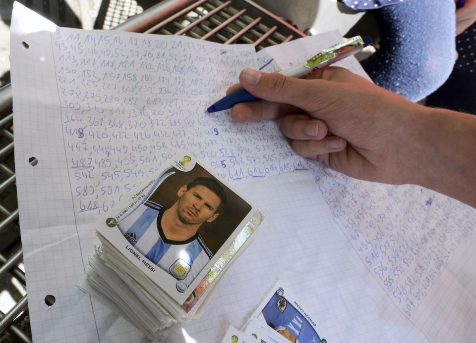 Un niño revisa su lista de pegatinas de la colección del álbum Panini de la Copa Mundial de fútbol para intercambiarlas con otro coleccionista, (Foto: REUTERS/Fabian Bimmer)