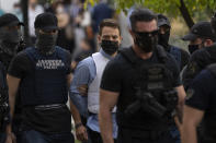 Babis Anagnostopoulos, center, escorted by police officers arrives to the prosecutor's office at a court, in Athens, Tuesday, June 22, 2021. The 33-year-old helicopter pilot and flight instructor Babis Anagnostopoulos has been detained as a suspect in the murder of his British wife Caroline Crouch, 20, outside Athens last month after publicly claiming she'd been killed during a brutal invasion of the couple's home, police said. (AP Photo/Petros Giannakouris)