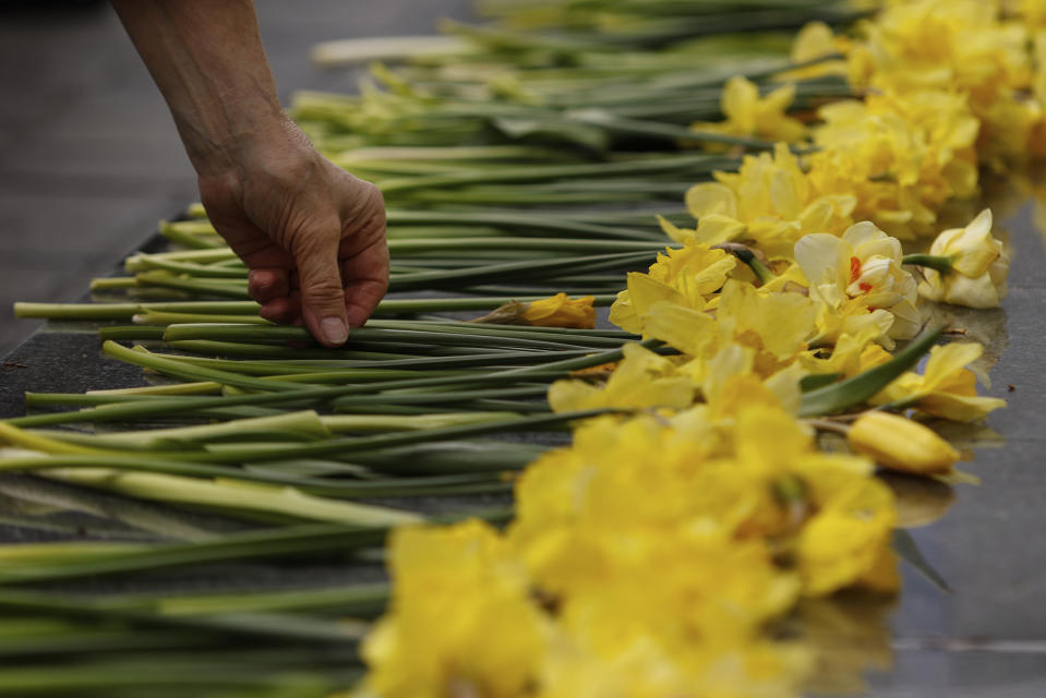 A woman places a yellow tulip at 'The Umschlagplatz' monument during personal unofficial observances marking the 80th anniversary of the Warsaw Ghetto Uprising in Warsaw, Poland, Wednesday, April 19, 2023. (AP Photo/Michal Dyjuk)