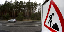 In this Wednesday, Jan. 8, 2020 photo car drives past a construction site sign at the site of the planned new Tesla Gigafactory in Gruenheide near Berlin, Germany. Tesla CEO Elon Musk said during an awards ceremony in Berlin in November 2019 that 'we have decided to put the Tesla Gigafactory Europe in the Berlin area.' The company will also set up an engineering and design center in Berlin, Musk said. He wrote on Twitter that the new plant 'will build batteries, powertrains & vehicles, starting with Model Y.' (AP Photo/Michael Sohn)