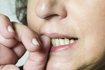 A close up of a woman biting her thumb nail