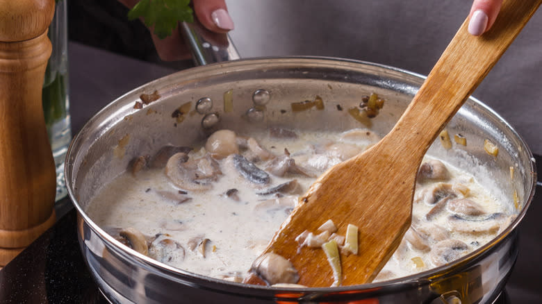 stirring creamy mushroom sauce