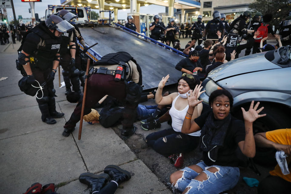 Protesters raise their hands on command from police as they are detained prior to arrest and processing at a gas station on South Washington Street, May 31, 2020, in Minneapolis. The image was part of a series of photographs by The Associated Press that won the 2021 Pulitzer Prize for breaking news photography. (AP Photo/John Minchillo)
