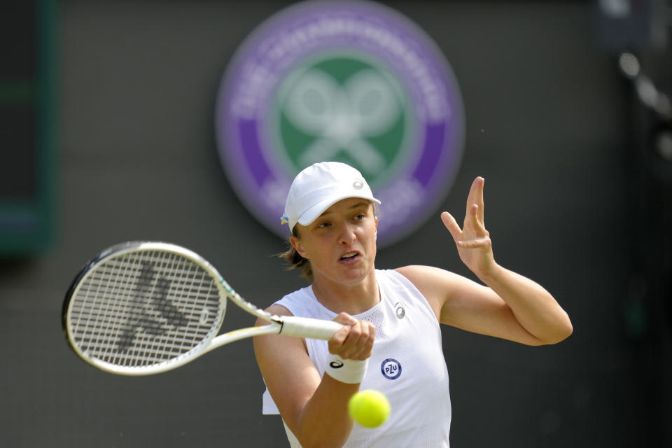 Poland's Iga Swiatek returns the ball to France's Alize Cornet during a third round women's singles match on day six of the Wimbledon tennis championships in London, Saturday, July 2, 2022. (AP Photo/Kirsty Wigglesworth)