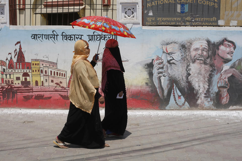 Indian Muslims women on way to a polling station to cast their votes walk past a mural showing Hindu holy men during the seventh and final phase of national elections in Varanasi, India, Sunday, May 19, 2019. Indians are voting in the seventh and final phase of national elections, wrapping up a 6-week-long long, grueling campaign season with Prime Minister Narendra Modi’s Hindu nationalist party seeking reelection for another five years. Counting of votes is scheduled for May 23. (AP Photo/Rajesh Kumar Singh)