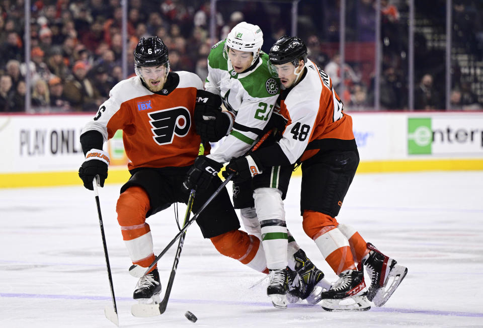 Dallas Stars' Jason Robertson, center, battles for the puck against Philadelphia Flyers' Travis Sanheim (6) and Morgan Frost (48) during the first period of an NHL hockey game Thursday, Jan. 18, 2024, in Philadelphia. (AP Photo/Derik Hamilton)