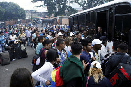 People queue to try to find a spot on a bus to travel to the city of San Antonio near the Colombian border at the bus station in San Cristobal, Venezuela December 14, 2017. REUTERS/Carlos Eduardo Ramirez