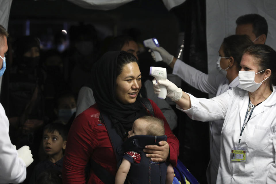 Health workers check the temperature of evacuated citizens from Afghanistan upon their arrival at Tirana International Airport in Tirana, Albania, Friday, Aug. 27, 2021. A government decision has planned that the Afghans may stay at least a year during which they will proceed with their application for special visas before they move on to the U.S. for final settlement. (AP Photo/Franc Zhurda)