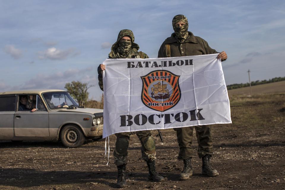 REFILE - CORRECTING TYPO An American who calls himself "Hunter" (R) holds his battalion flag with a fellow rebel near the town of Yasynuvata September 26, 2014. With his face hidden behind a camouflage balaclava and an assault rifle slung over his shoulder, "Hunter" looks like other separatist fighters in eastern Ukraine. What distinguishes him from his brothers in arms in the Vostok (East) battalion, an irregular pro-Russian militia fighting government forces, is his American accent - and English is the only language he knows. Picture taken September 26, 2014. REUTERS/Marko Djurica (UKRAINE - Tags: POLITICS CIVIL UNREST CONFLICT MILITARY)