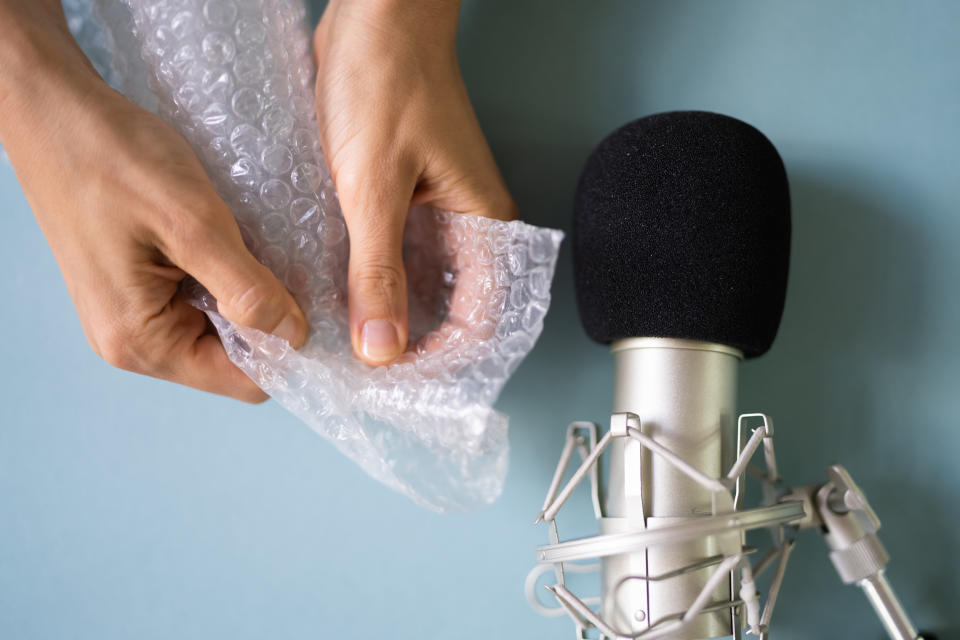 A person popping bubble wrap against a microphone