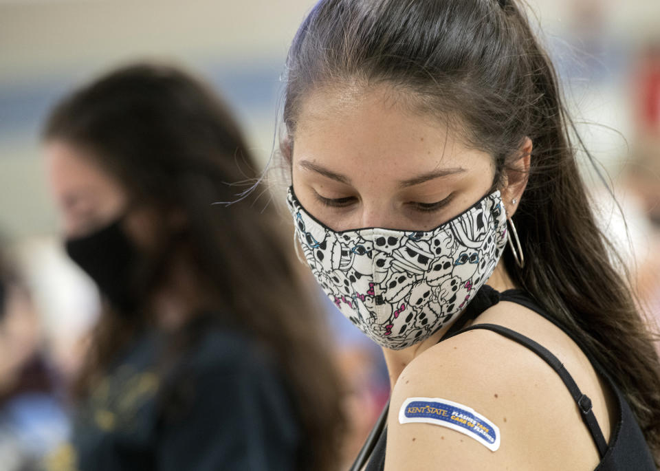 FILE - In this Thursday, April 8, 2021, file photo, Kent State University student Regan Raeth, of Hudson, Ohio, looks at her vaccination bandage as she waits for 15 minutes after her shot in Kent, Ohio. On Wednesday, May 12, 2021, Gov. Mike DeWine announced the end of the state's mask mandate as new COVID-19 cases decrease and more Ohioans get vaccinated. DeWine said the mask mandate will end June 2 except for nursing homes and assisted living facilities. (AP Photo/Phil Long, File)