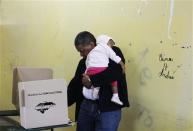 A man holds a child while casting his vote in the presidential election at a polling station in Tegucigalpa November 24, 2013. REUTERS/Jorge Cabrera