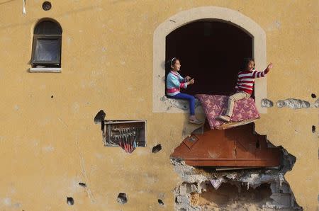 Palestinian girls play at their family's house, that witnesses said was damaged by Israeli shelling during a 50-day war last summer, in Khan Younis in the southern Gaza Strip, March 10, 2015. REUTERS/Ibraheem Abu Mustafa