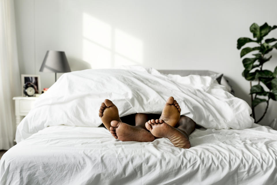 Two people's feet sticking out from under the bed covers