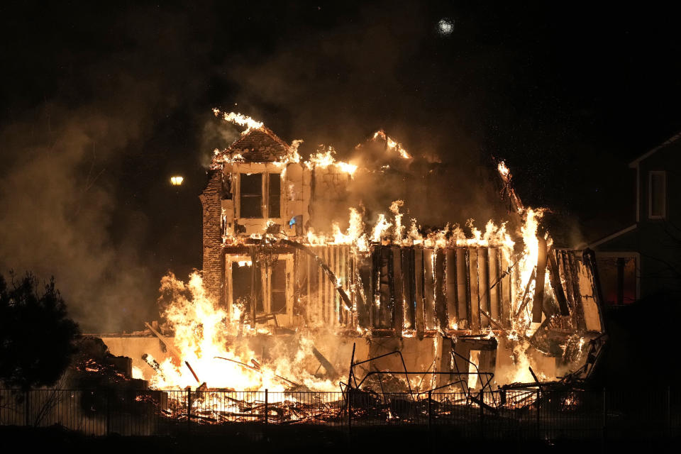 File—Homes burn as a wildfire rips through a development near Rock Creek Village, Thursday, Dec. 30, 2021, near Broomfield, Colo. Just over a year after the most destructive wildfire burned in Colorado's history, a bill is being introduced in the state's legislature to create a $2-million pilot program to use cameras likely equipped with artificial intelligence technology in high-risk areas to help identify fires before they can burn out of control. (AP Photo/David Zalubowski, File)