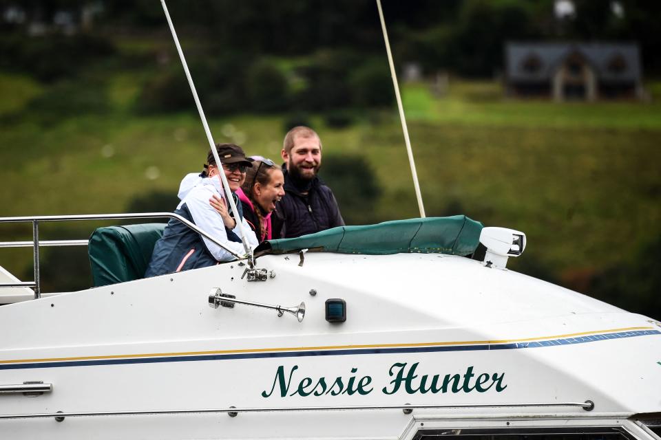 People aboard the vessel 'Nessie Hunter' react as it arrives back at the moorings in Drumnadrochit on Loch Ness on August 27, 2023. The biggest search for the Loch Ness Monster in five decades got underway in the Scottish Highlands, as researchers and enthusiasts from around the world braved pelting rain to try to track down the elusive Nessie. The expedition deployed drones with thermal scanners, boats with infrared cameras and an underwater hydrophone to try to unravel a mystery that has captivated the world for generations. (Photo by Andy Buchanan / AFP) (Photo by ANDY BUCHANAN/AFP via Getty Images)