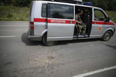 A shell crater is seen as Ukrainian serviceman guards a car with sappers, in the eastern Ukrainian village of Semenovka July 13, 2014. REUTERS/Gleb Garanich