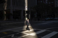 A worker crosses an intersection in San Francisco's financial district mid-afternoon, during what would've been a bustling time before the COVID-19 pandemic, on Wednesday, Oct. 21, 2020. The area remains largely devoid of activity as many employees continue to work from home. (AP Photo/Noah Berger)