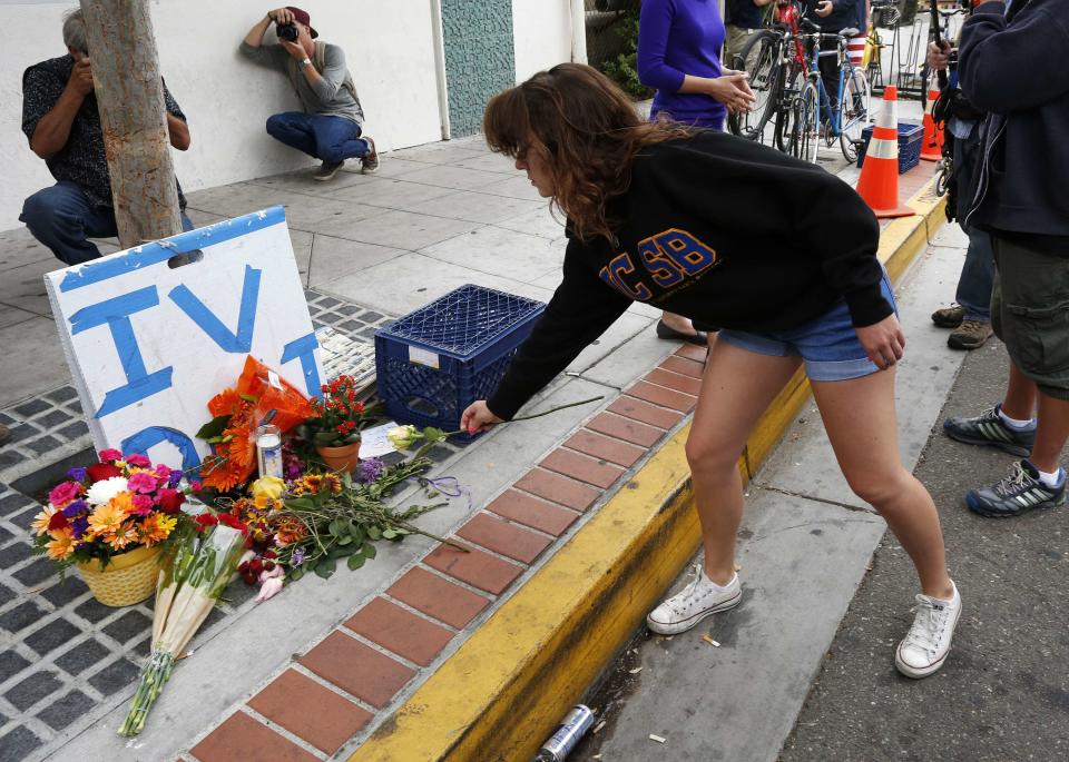 UC Santa Barbara student Allie Nelch places a flower at a makeshift shrine at one of nine crime scenes after series of drive -by shootings that left 7 people dead in the Isla Vista section of Santa Barbara