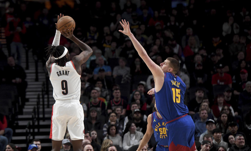 Portland Trail Blazers forward Jerami Grant, left, looks to shoot over Denver Nuggets center Nikola Jokic, right, during the first half of an NBA basketball game in Portland, Ore., Friday, Feb. 23, 2024. (AP Photo/Steve Dykes)