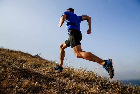 A man in workout apparel running up a hill.