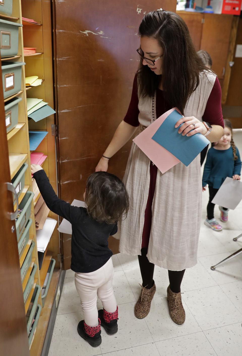 Consumer sciences teacher Jennifer Biese helps a preschool student pick art supplies during Appleton East's Little Patriots Preschool.