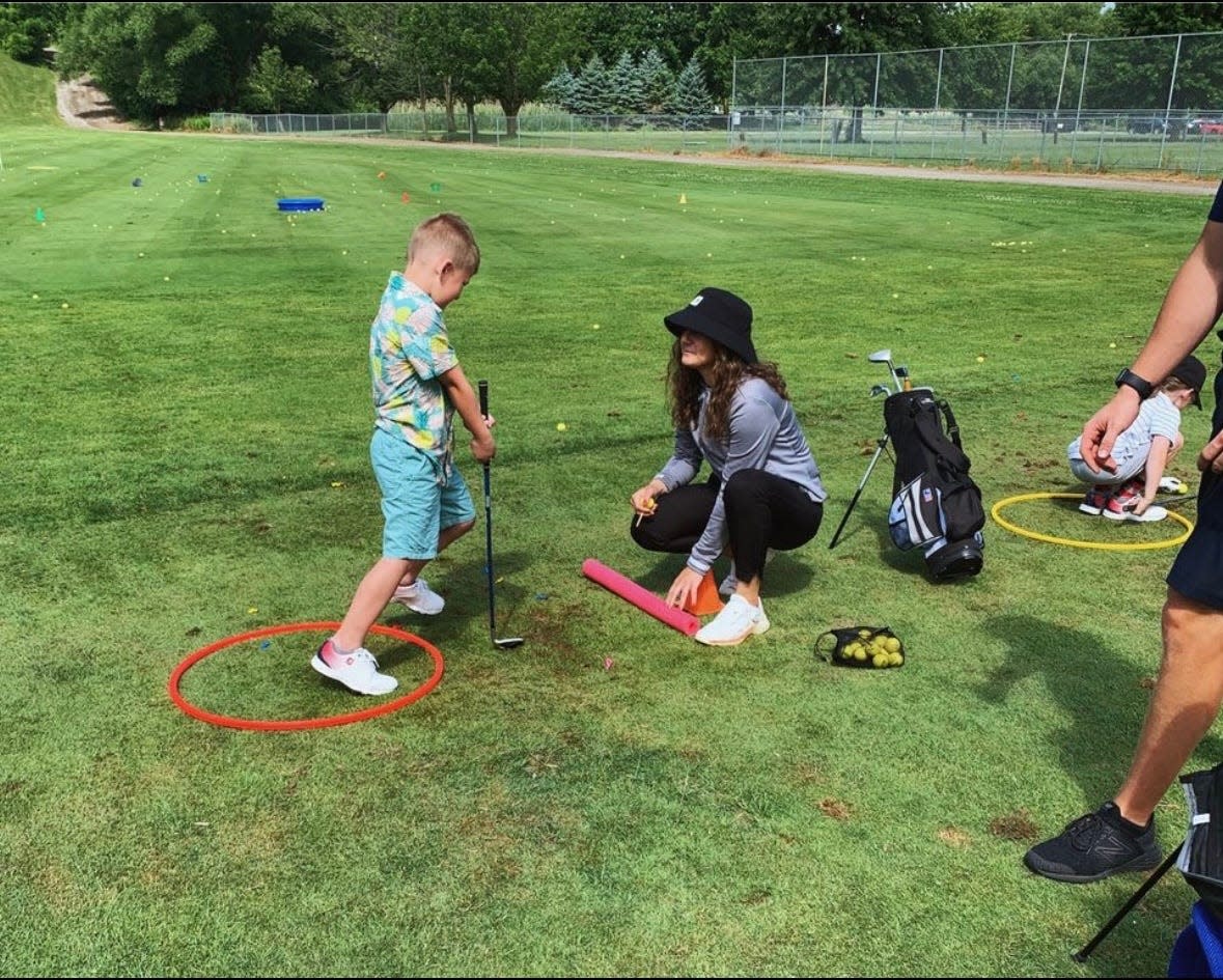 Madeline Blum (right) works with a boy in the junior golf program at Elks Golf Club in Port Huron in 2023.