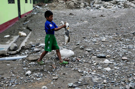 A child carries a cat after the Rimac river overflowed near the Central Highway in Huarochiri, Lima, Peru, March 23, 2017. REUTERS/Guadalupe Pardo