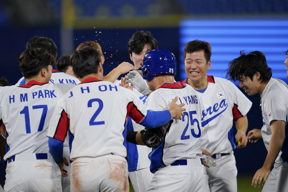 South Korea's Euiji Yang celebrates with teammates after being hit by pitch to walk in the winning run in the tenth inning of a baseball game against Israel at the 2020 Summer Olympics, Thursday, July 29, 2021, in Yokohama, Japan. South Korea won 6-5.(AP Photo/Sue Ogrocki)
