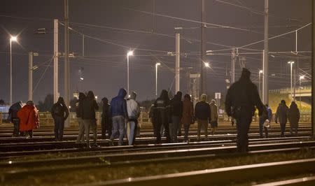 Police officers (C and R) push back migrants walking on the railway tracks of the freight shuttle leading to the entrance of the Channel Tunnel in Calais, France, October 14, 2015. REUTERS/Philippe Wojazer