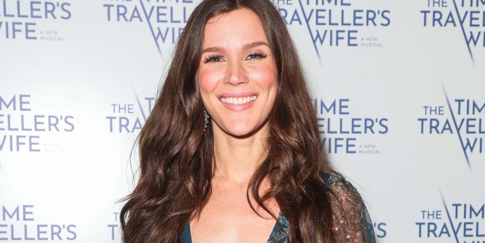 Joss Stone, a woman with long brown hair wearing a teal floral dress, poses and smiles at the camera