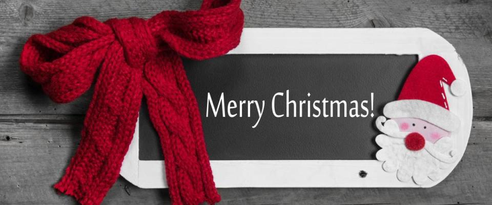 Red bow on menu board with Merry Christmas message on wooden background