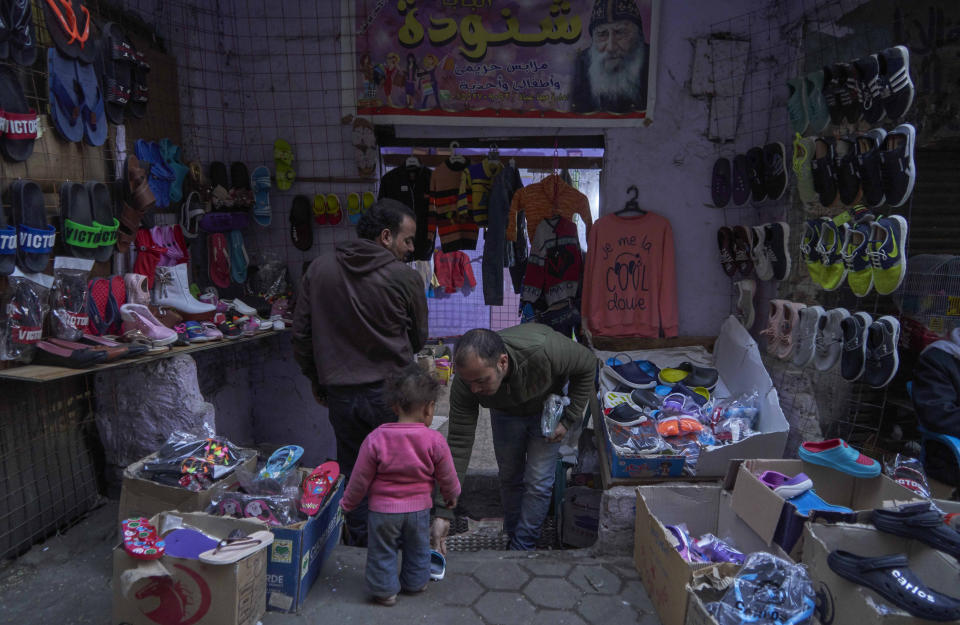 A child tries on new shoes at a street shop display for customers to buy new shoes and clothing, in preparation for the Coptic Christmas celebration, at a residential and industrial area of eastern Cairo, Egypt, Monday, Jan. 6, 2020. (AP Photo/Hamada Elrasam)