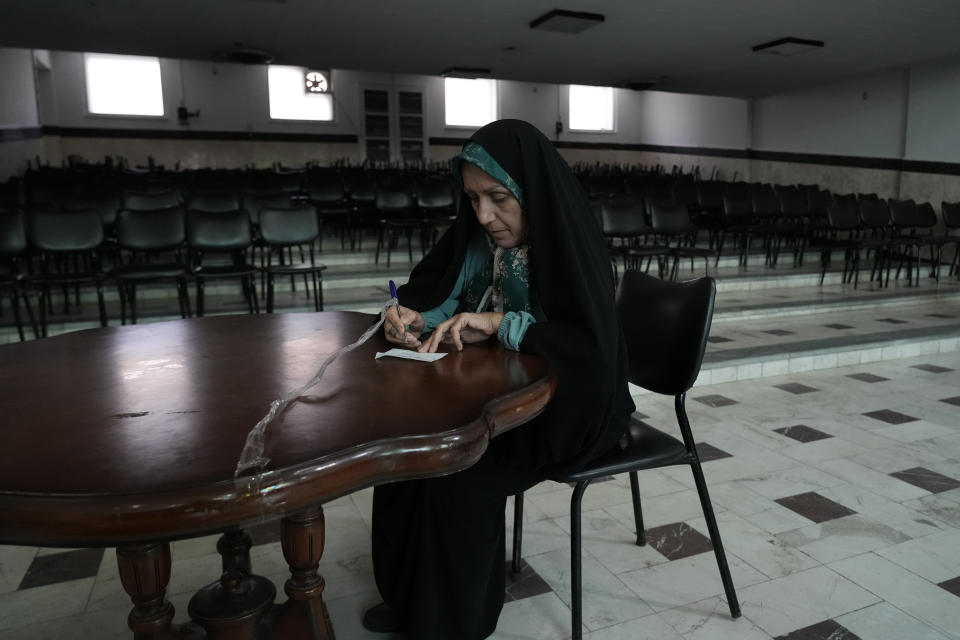 An Iranian woman fills out her ballot for the presidential runoff election at a polling station in Tehran, Iran, Friday, July 5, 2024. Iranians began voting Friday in a runoff election to replace the late President Ebrahim Raisi, killed in a helicopter crash last month, as public apathy has become pervasive in the Islamic Republic after years of economic woes, mass protests and tensions in the Middle East. (AP Photo/Vahid Salemi)