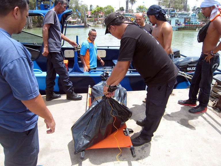 This photo, taken on August 4, 2013, and released by the Malaysian Maritime Enforcement Agency, shows officials at the Maritime office in Tanjung Sedili in Johor state transporting three victims found at sea after a wooden boat that was believed to be carrying 44 people, sank off the coast