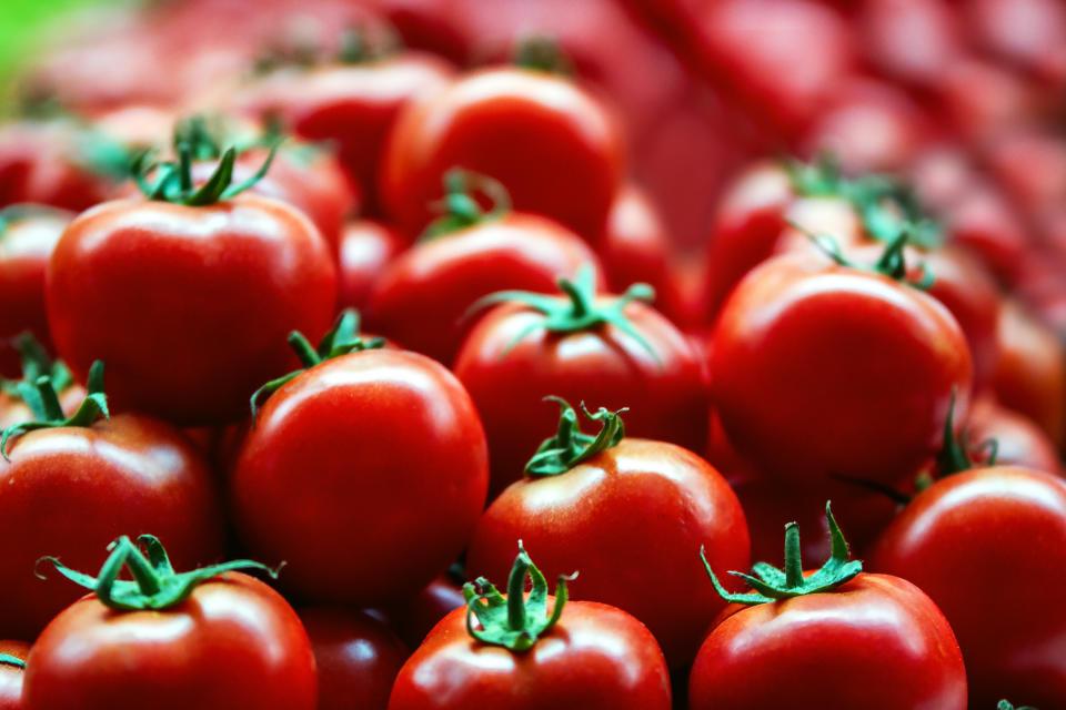 Lots of red fresh ripe tomatoes close up in the supermarket. Vegetables harvest. Food natural background