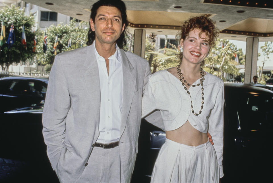 American actor Jeff Goldblum, wearing a grey suit over a white shirt, and his wife, American actress Geena Davis, who wears a white outfit with her midriff exposed, attend the 61st Academy Awards Nominees Luncheon, held at the Beverly Hilton Hotel in Beverly Hills, California, 21st March 1989 (Photo by Vinnie Zuffante/Getty Images)