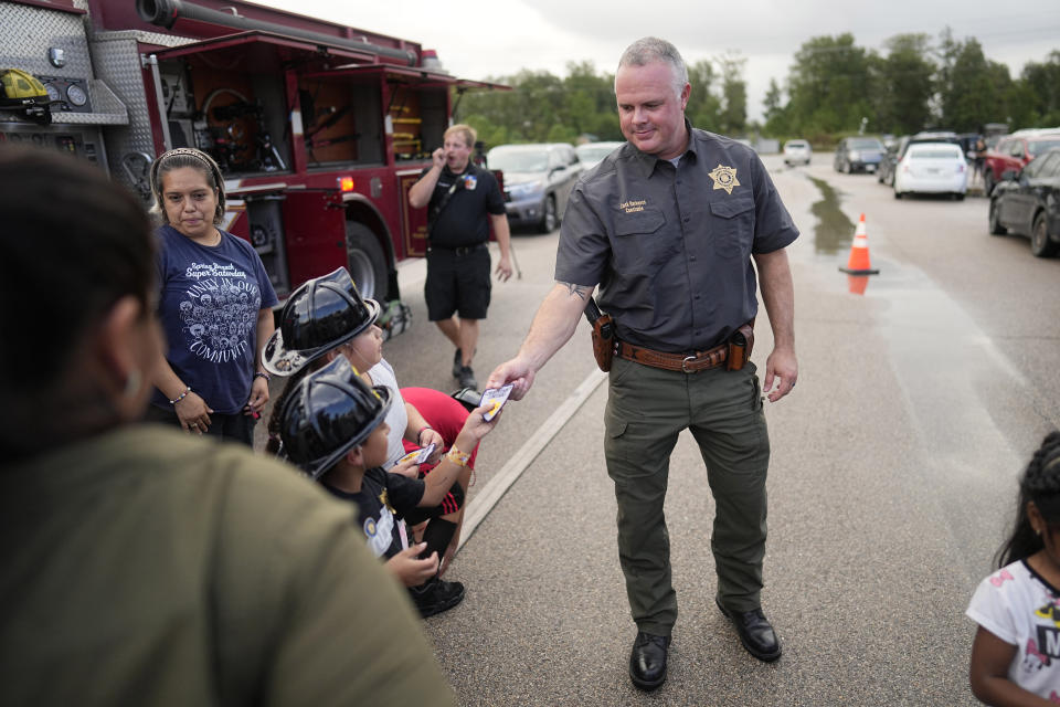 Liberty County Precinct 6 Constable Zack Harkness hands out patches during a National Night Out event in the Colony Ridge development Tuesday, Oct. 3, 2023, in Cleveland, Texas. For weeks in Texas, conservative media and GOP activists have been pushing unsubstantiated claims that Colony Ridge has become a magnet for immigrants living in the U.S. illegally and that cartels control pockets of the neighborhood. (AP Photo/David J. Phillip)