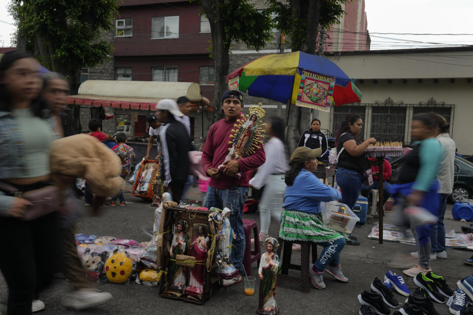 FILE - People mill about as a vendor hawks religious statues during a city fair, Aug. 15, 2023. Guatemalans head to the polls Sunday, Aug, 20, to elect a new president, in a runoff election. (AP Photo/Moises Castillo, File)