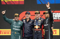 Winner Red Bull Racing's Max Verstappen, of the Netherlands, and his technical director, Adrain Newey, stand next to second place finisher Aston Martin driver Fernando Alonso, left, of Spain, and third place Mercedes driver Lewis Hamilton of the United Kingdom, during victory ceremonies following the Formula One Canadian Grand Prix auto race Sunday, July 18, 2023, in Montreal. (Paul Chiasson/The Canadian Press via AP)