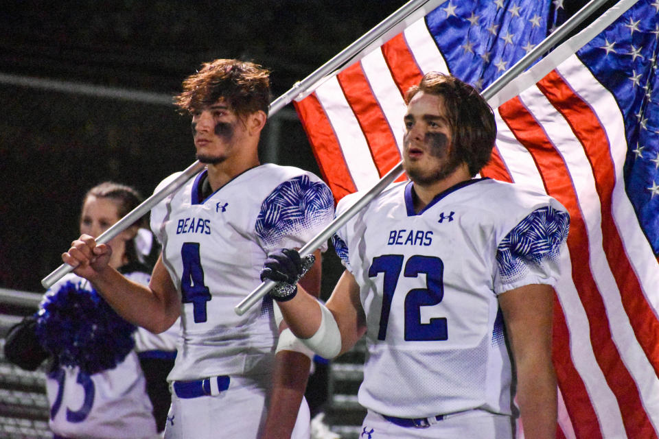 Pleasant Valley's James Syracuse (No. 4) and Michael Barrett (No. 72) stand with U.S. flags for the national anthem in Swiftwater on Friday, Oct. 1, 2021. Pleasant Valley defeated Pocono Mountain East, 42-8, in the Old Oaken Bucket game.