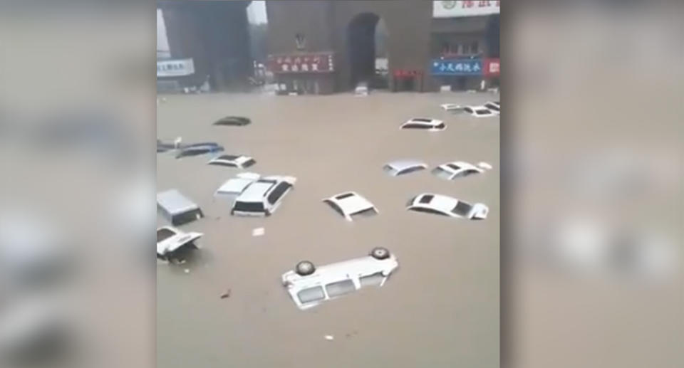 Dozens of vehicles, some overturned, float in a flooded street. Source: Weibo