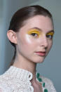 <p>A model wears bright yellow eyeshadow and a touch of cheek highlighter. (Photo: NARS) </p>