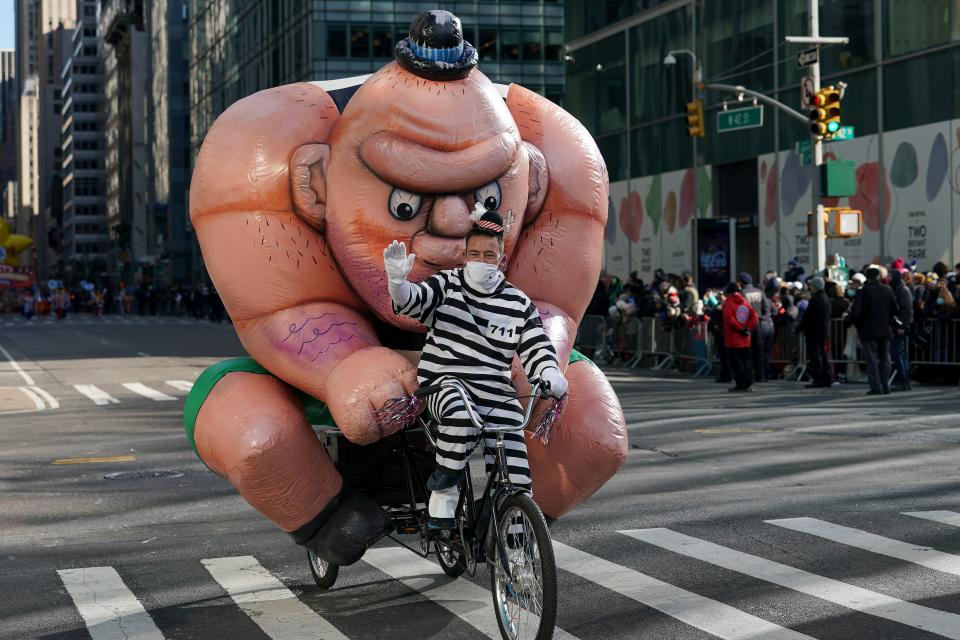 The Tough Guy balloon is driven down Sixth Avenue on a bicycle during the Macy's Thanksgiving Day Parade, Thursday, Nov. 25, 2021, in New York. The Macy's Thanksgiving Day Parade is returning in full, after being crimped by the coronavirus pandemic last year.  