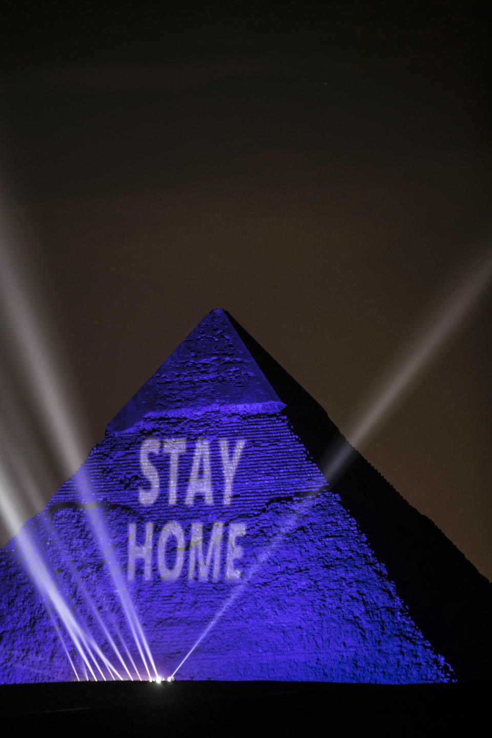 A picture on April 18, 2020, shows the Great Pyramids lit in blue with the message "Stay Home" outside the Egyptian capital of Cairo.