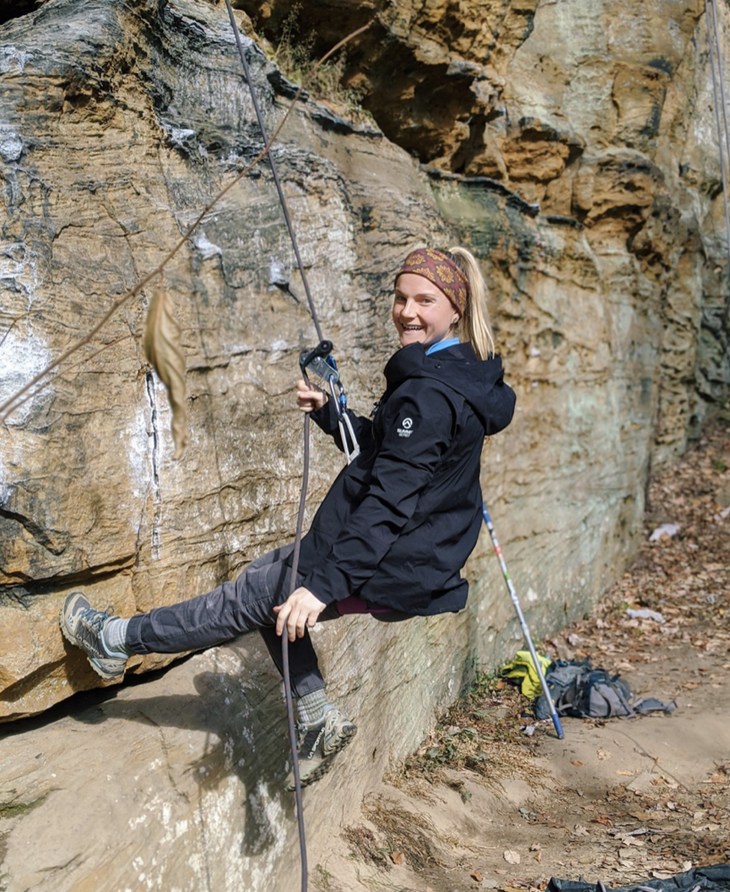 Jennifer Yarin belays a sport climb outside in the sun.