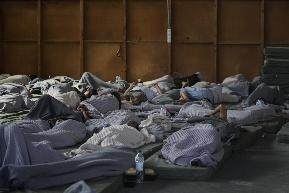 Survivors of a shipwreck sleep at a warehouse at the port in Kalamata town, about 240 kilometers (150 miles) southwest of Athens, Wednesday, June 14, 2023. A fishing boat carrying migrants capsized and sank off the coast of Greece on Wednesday, authorities said, leaving at least 78 people dead and many dozens feared missing in one of the worst disasters of its kind this year. (AP Photos/Thanassis Stavrakis)