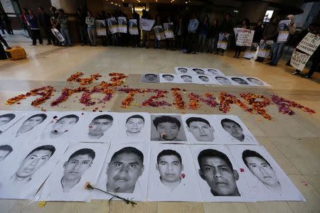 Portraits of some of the 43 missing students of the Ayotzinapa teachers training college Raul Isidro Burgos are placed on the floor as students take part in a protest in support of them outside the Mexican Embassy in Bogota November 7, 2014. REUTERS/John Vizcaino