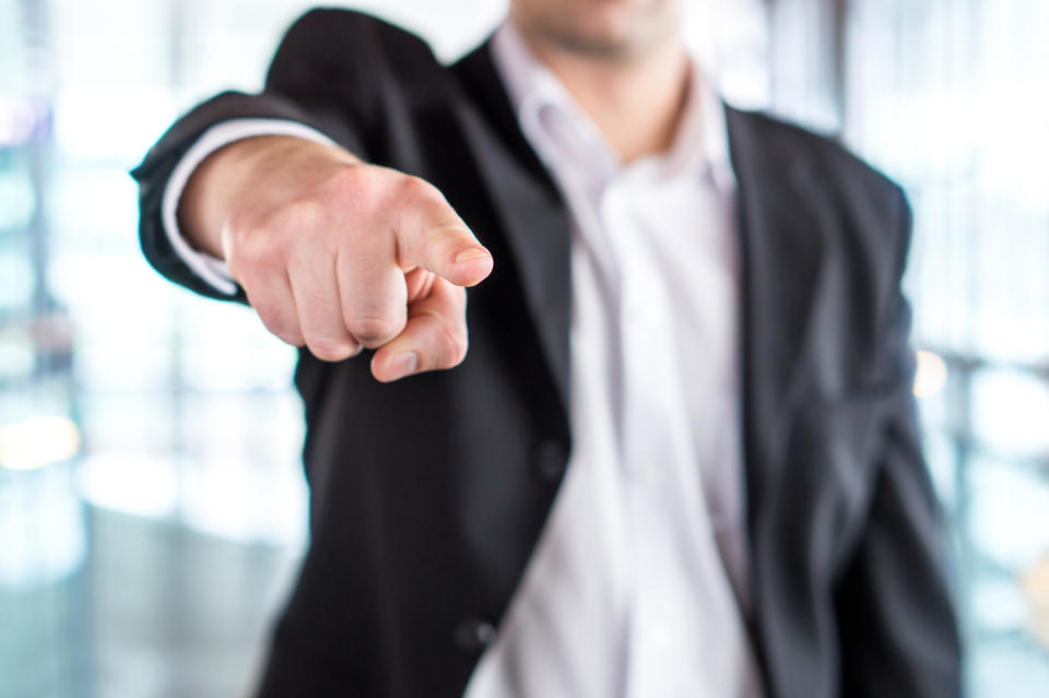 A man in a suit aggressively pointing towards the camera.