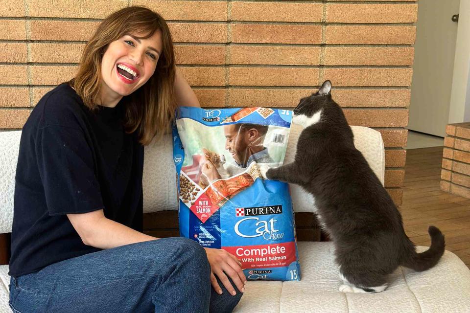 <p>Purina Cat Chow</p> Mandy Moore with a cat trying to getting into a bag of Purina Cat Chow